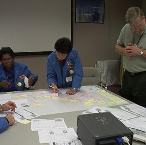 A group of people sitting around a table with papers on it.