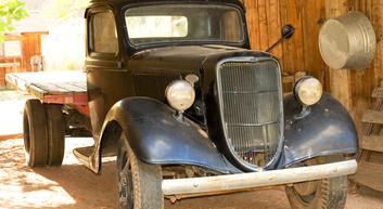 A black truck parked in front of a wooden wall.